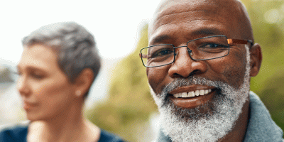 Man smiling at camera with his spouse in the background