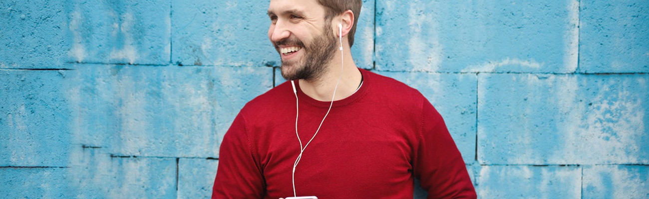 Man standing by a wall listening to head phones